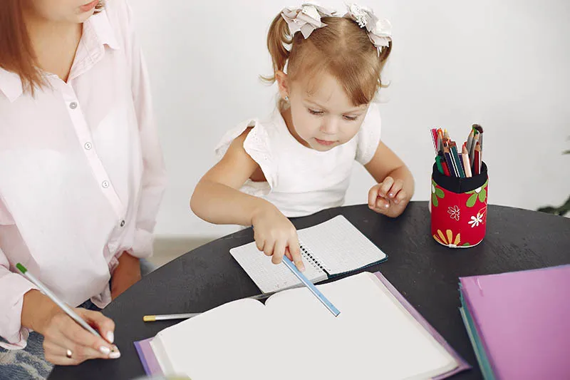 Babysitter with litthe girl studying at home